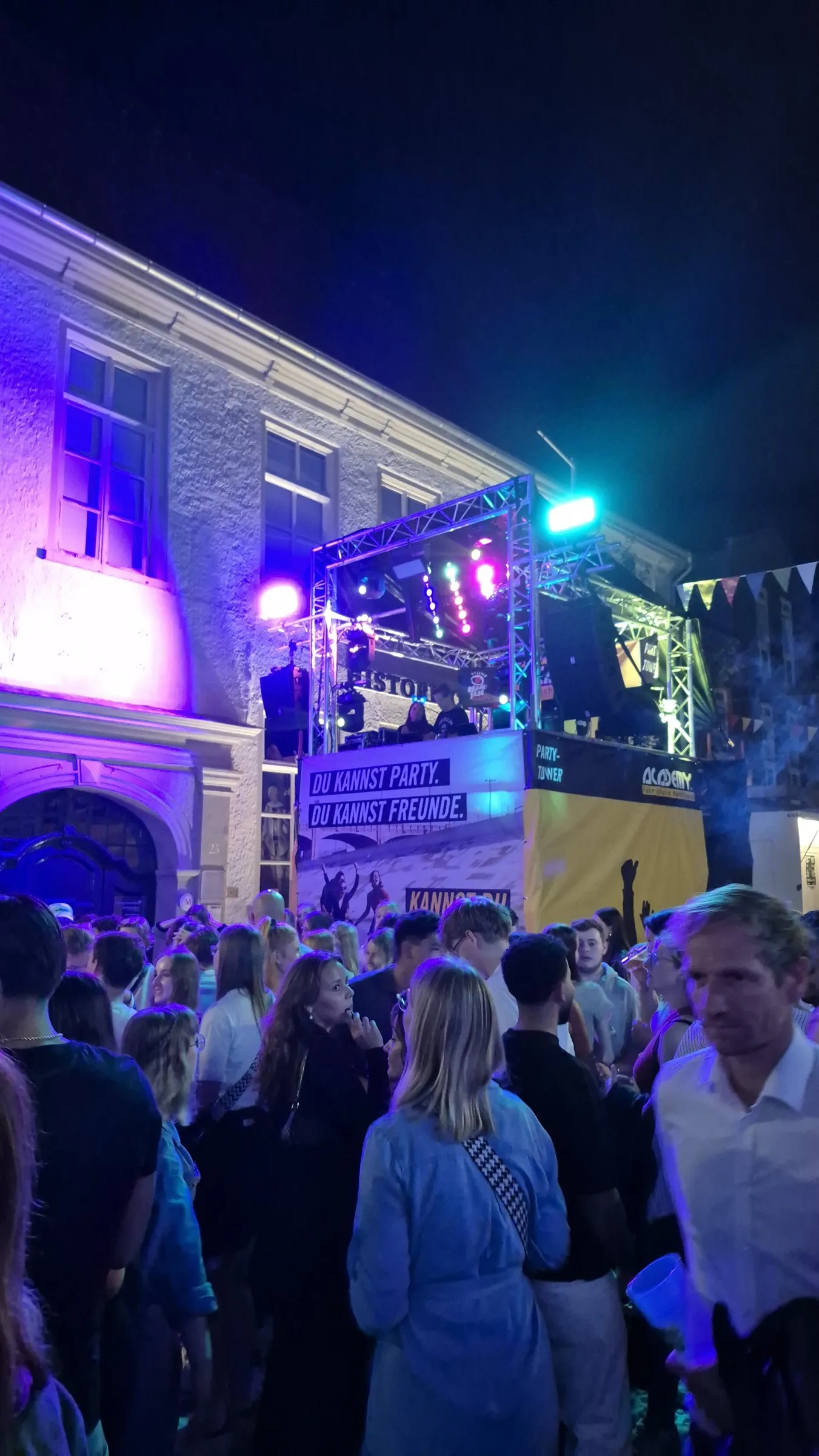 Der Discotower bei Nacht, davor tanzende Gäste