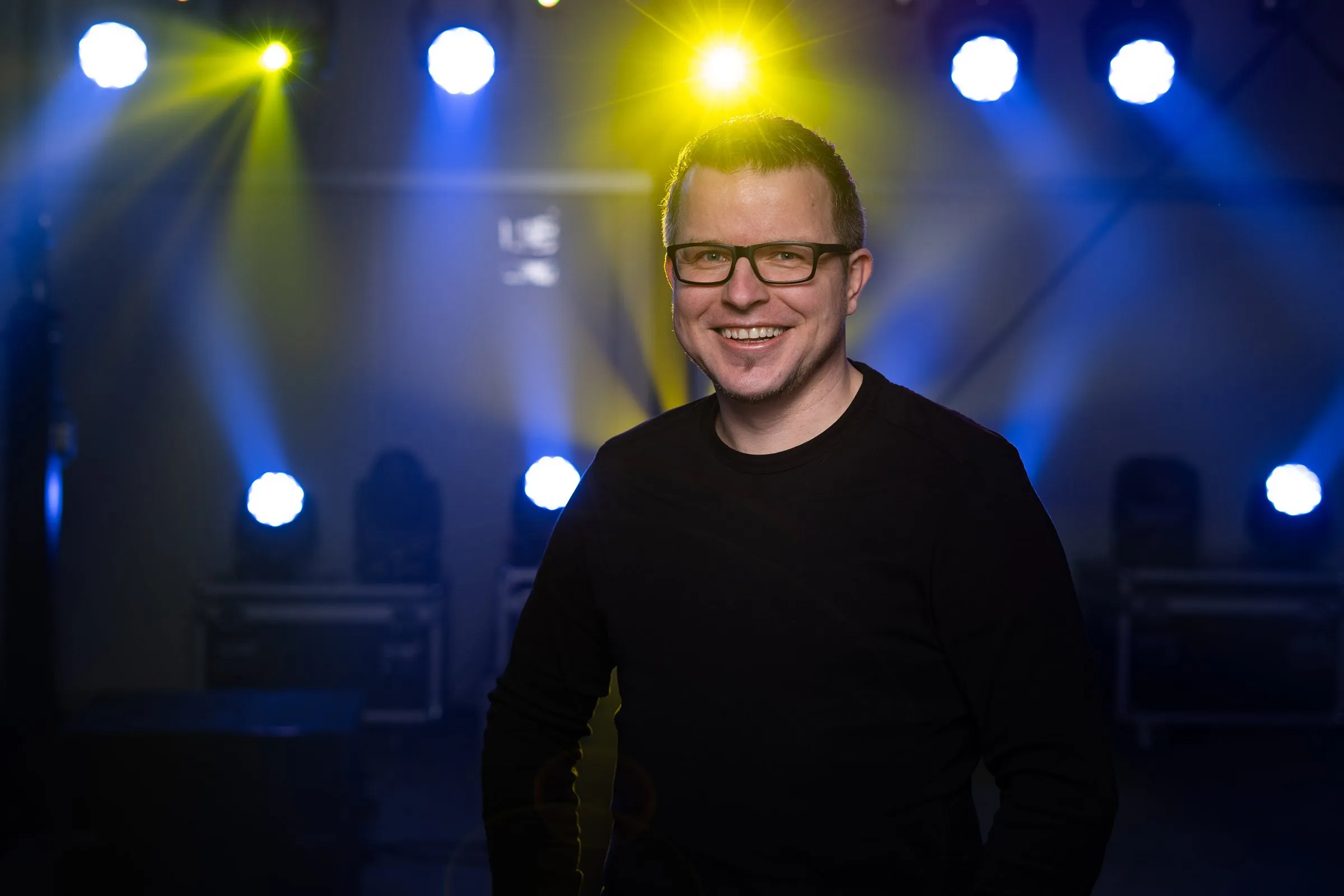 DJ Matthias Steenblock vor blauen und gelben Scheinwerfern