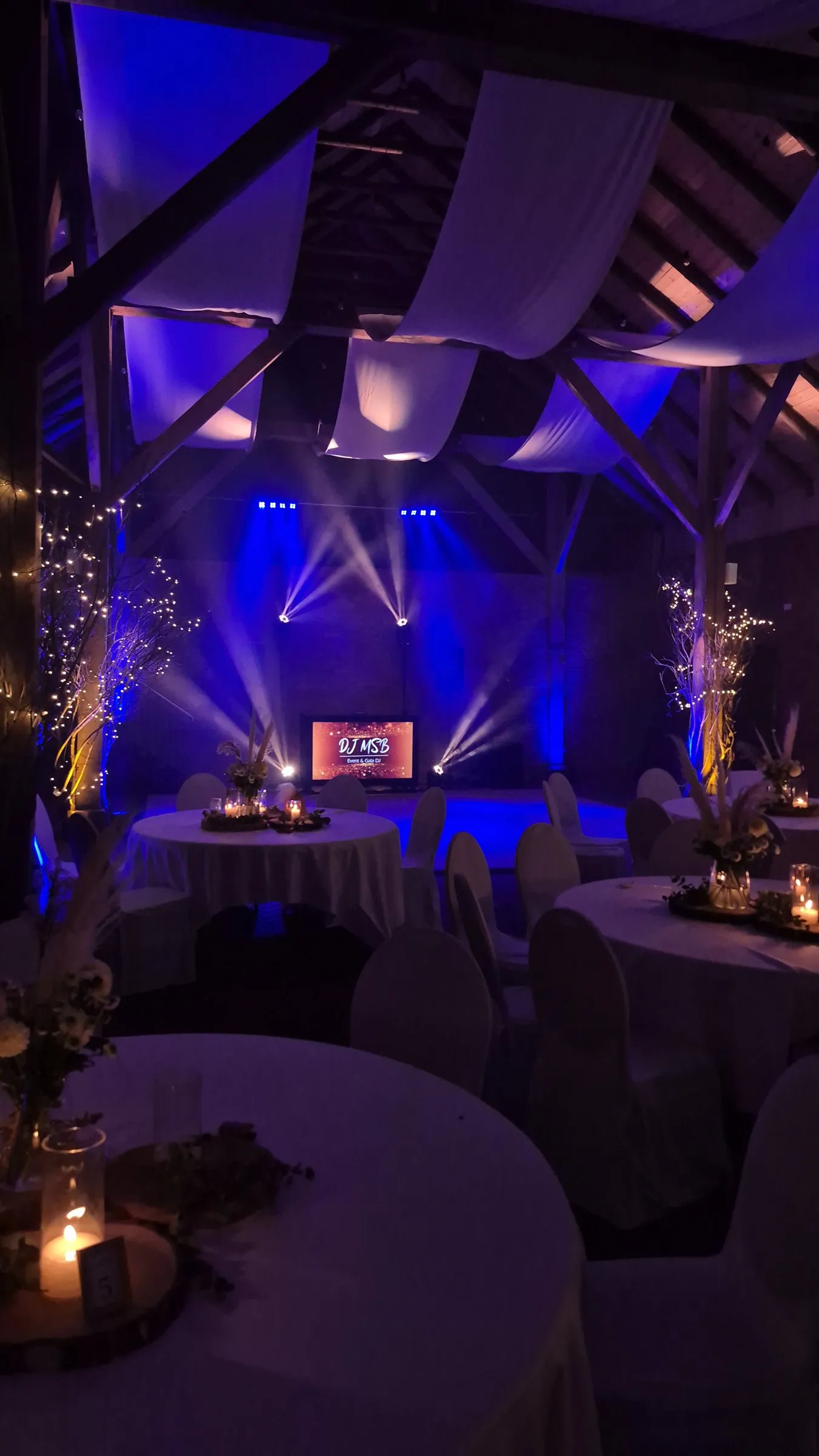 Festlich gedeckte Scheune mit Lichtstrahlen und Screen in blauem Licht